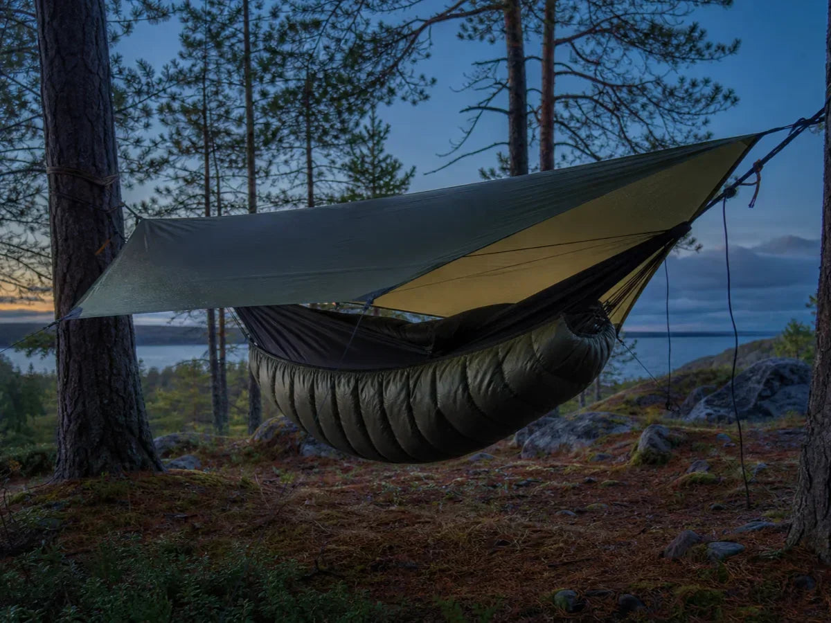A hammock underquilt hanging beneath a hammock under a tarp at dusk